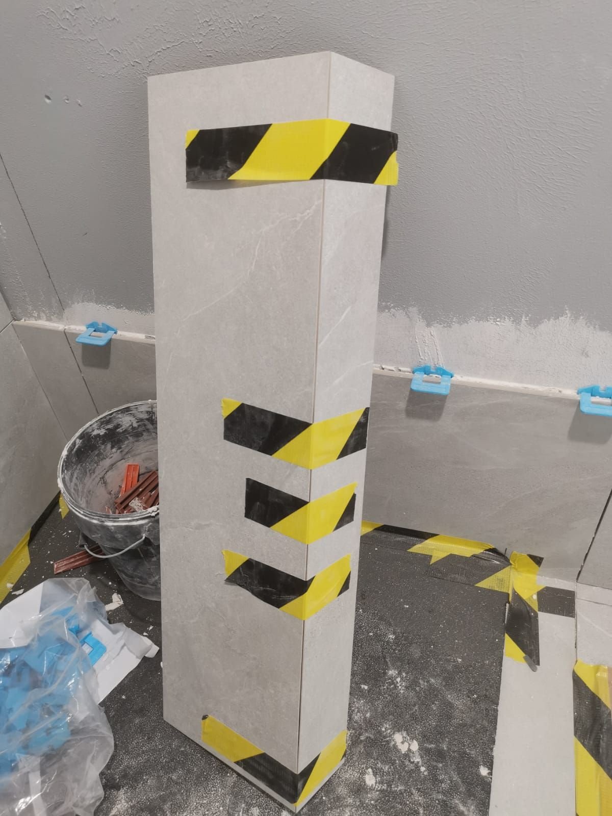 Colonna rivestita in gres con angoli tagliati a 45 gradi e spigoli protetti durante il cantiere